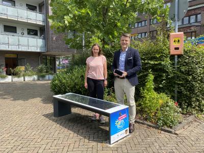 Im Vordergrund ist eine Solarbank zu sehen. Dahinter stehen die Klimaschutzmanagerin Bibiana Piskurek und Bürgermeister Dirk Haarmann.